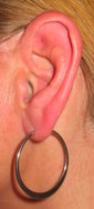 A woman's ear with a large silver earring.
