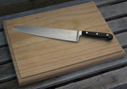 A wooden chopping board with a chef's knife.