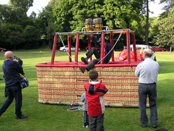A wicker balloon basket capable of holding 16 passengers. The pilot is climbing out after some pre-flight tests