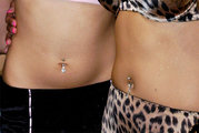 Two female navels, pierced and fitted with barbell jewelry.