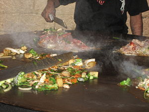 Food cooking on a Mongolian barbecue griddle.