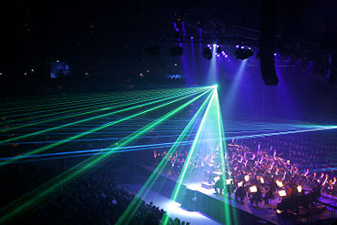 Low-intensity lighting and haze in a concert hall allows laser effects to be visible