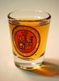 A 2 fl oz shot glass with the Virginia Tech university seal; filled with Rum.