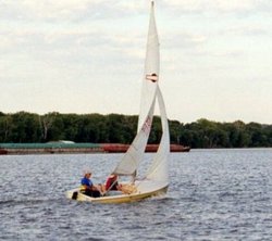 A sailboat (racing dinghy) and barge share the Mississippi River