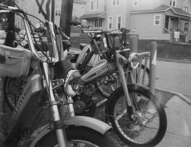 A picture of several mopeds from a ride sponsored by the Moped Army.  In the front is a Garelli, followed by a Motobecane, and in the rear is a Sachs.